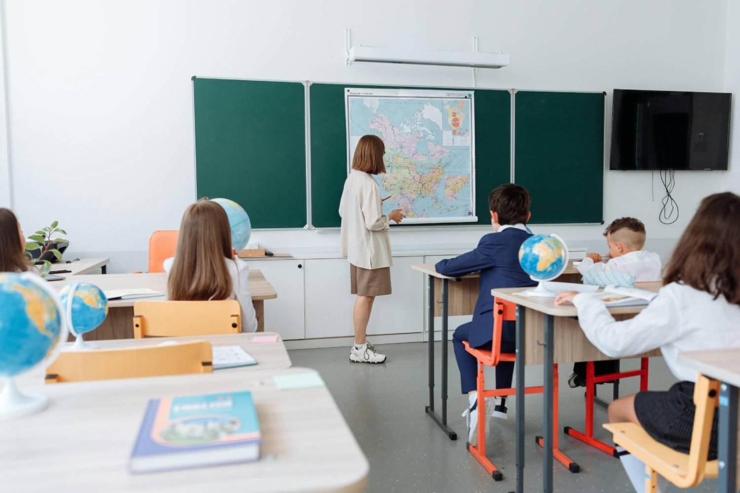 nauczycielka w klasie z uczniami tłumaczy lekcję