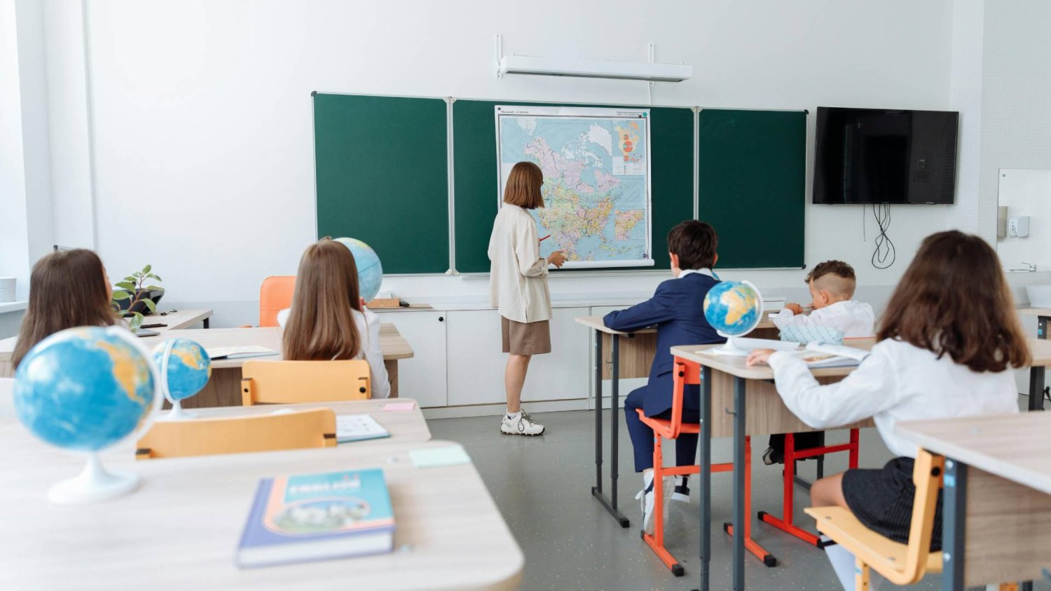 nauczycielka w klasie z uczniami tłumaczy lekcję