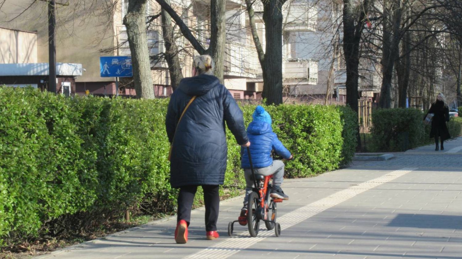 Mama z dzieckiem na spacerze w grubych zimowych ubraniach.