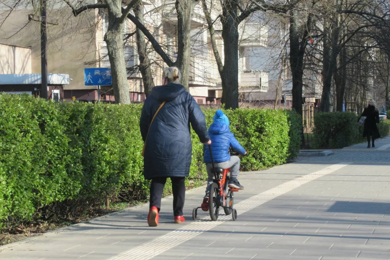 Mama z dzieckiem na spacerze w grubych zimowych ubraniach.