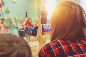 Dzieci występują na jasełkach, matka nagrywa przedstawienie telefonem.