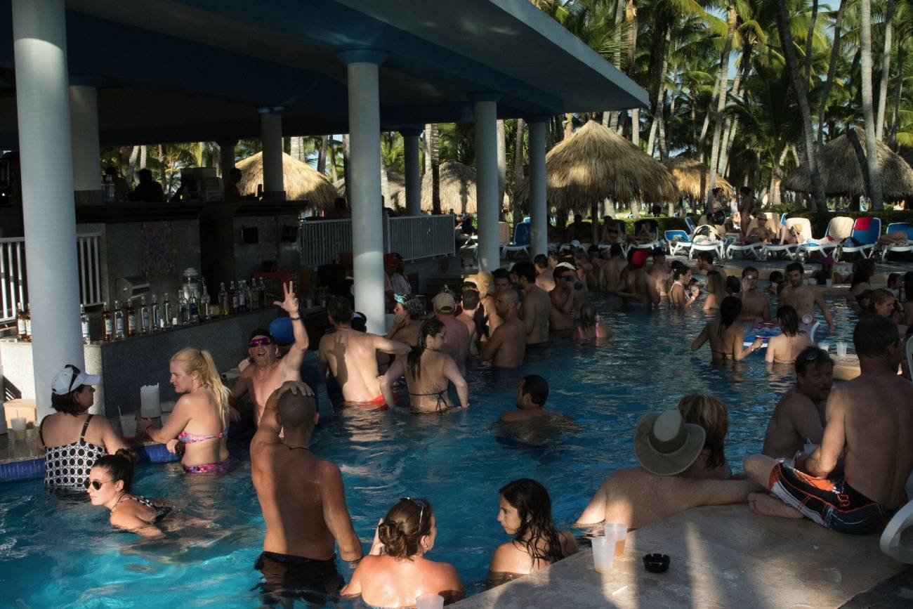 Goście w hotelu bawią się w basenie i piją alkohol.