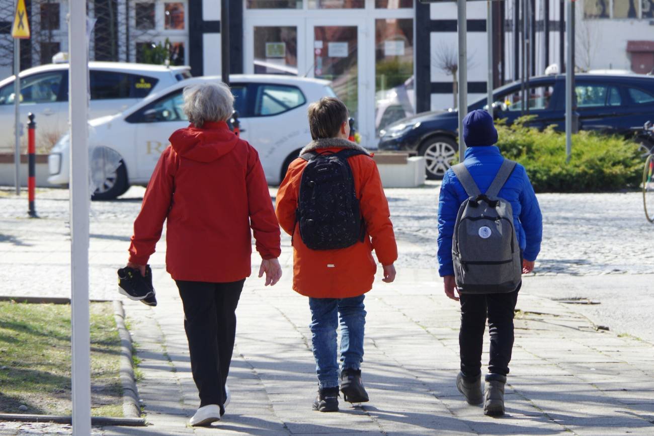 Uczniowie z plecakami idą do szkoły.