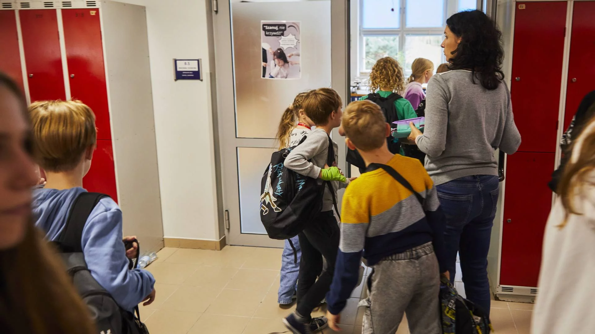 Nauczycielka z uczniami na szkolnym korytarzu