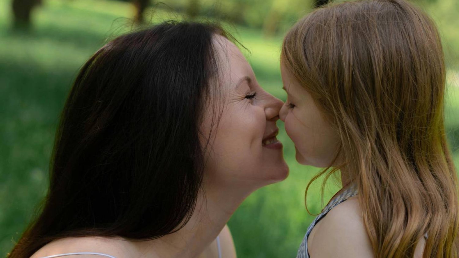 Mama i córka w parku uśmiechają się do siebie. Mama i córka w parku uśmiechają się do siebie.