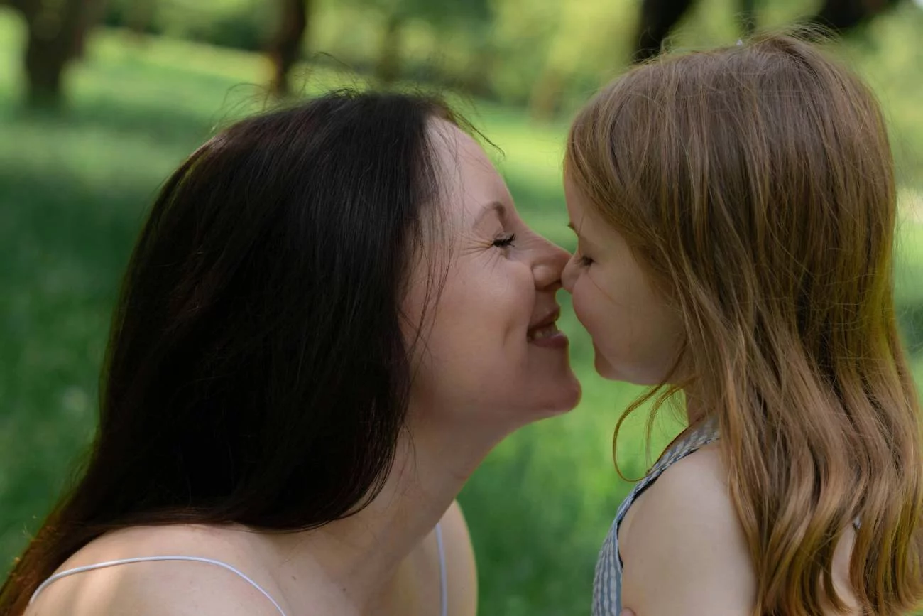 Mama i córka w parku uśmiechają się do siebie. Mama i córka w parku uśmiechają się do siebie.