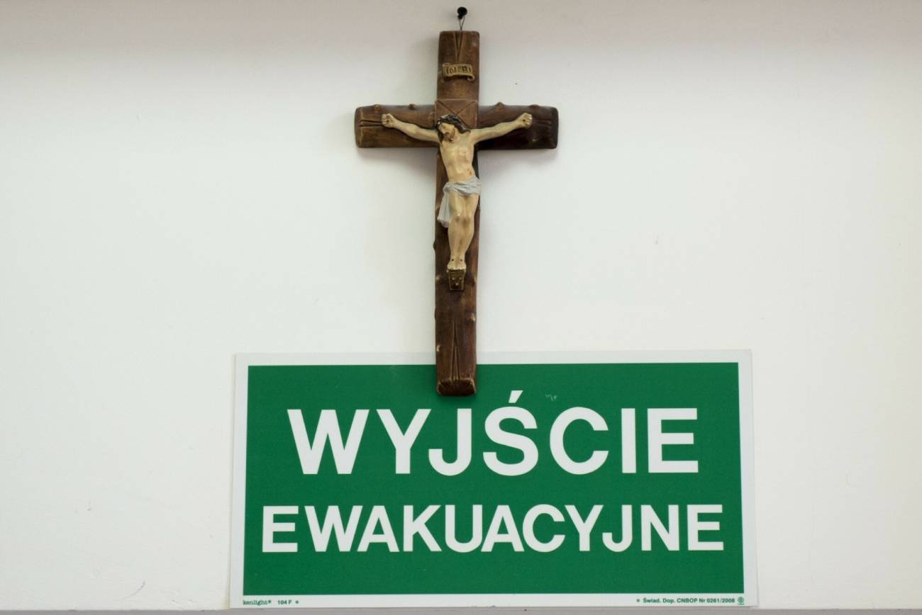 Krzyż na ścianie i napis: "wyjście ewakuacyjne"