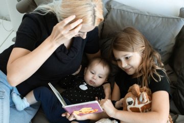 Mama spędza czas z dziećmi na czytaniu książki.