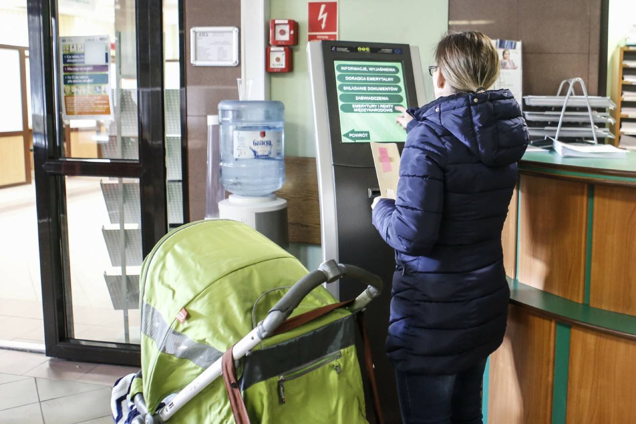 Matka z wózkiem w urzędzie, składa dokumenty o świadczenia na dziecko 2024.