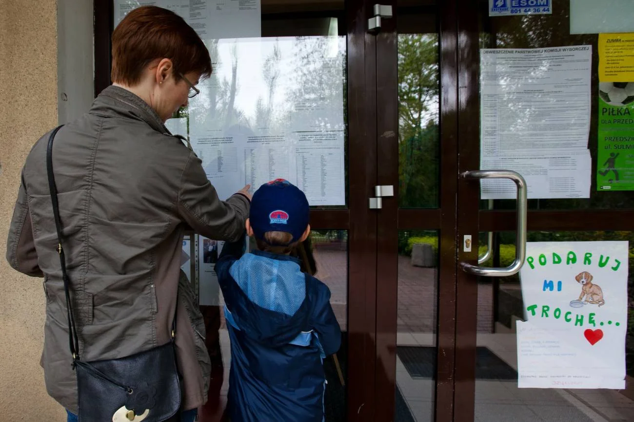 Mama z dzieckiem sprawdzają listy w przedszkolu.
