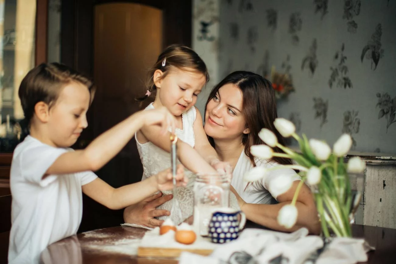Mama z dwójką dzieci gotuje w kuchni.