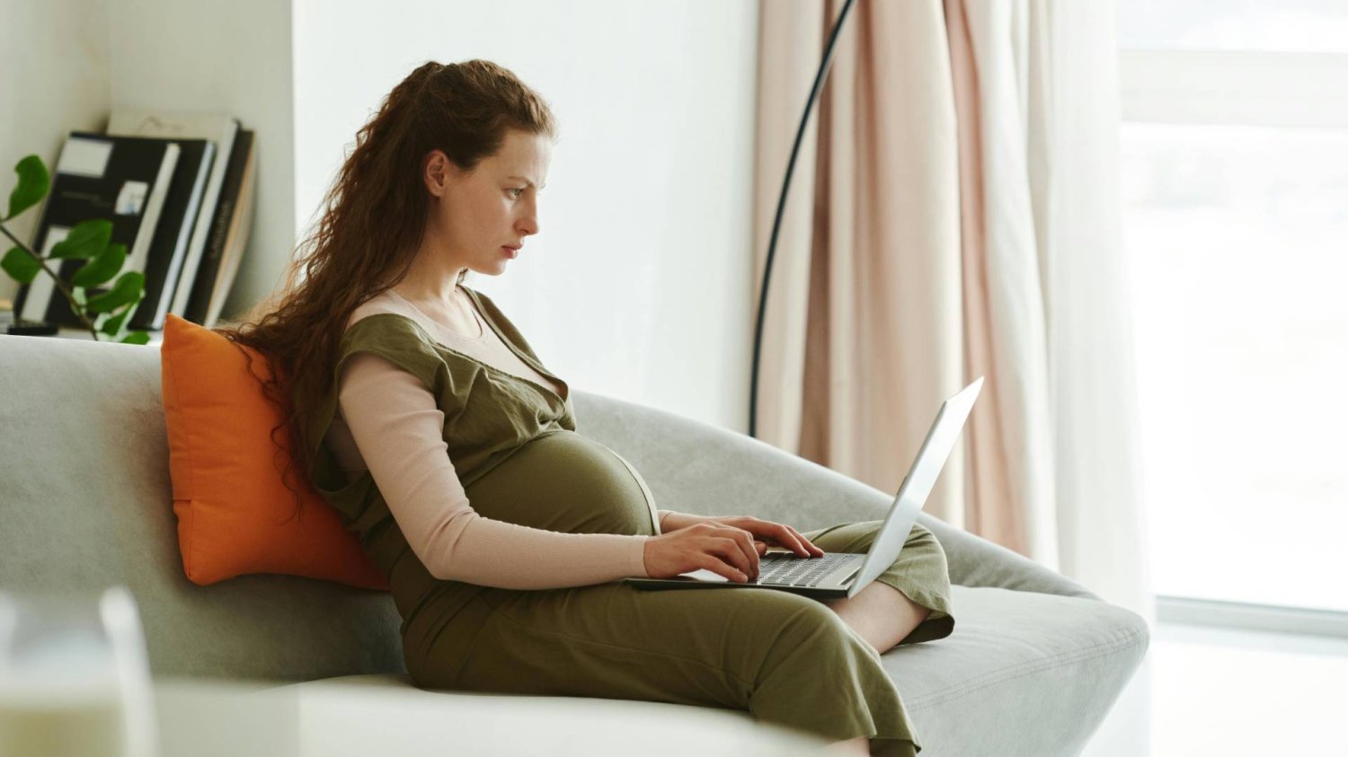 kobieta w ciąży pracuje w domu na laptopie