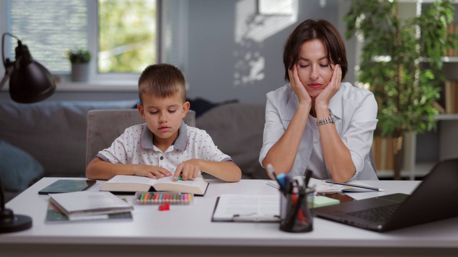 mama z synem wykonują swoje zadania: dziecko dorabia lekcje, mama pracuje