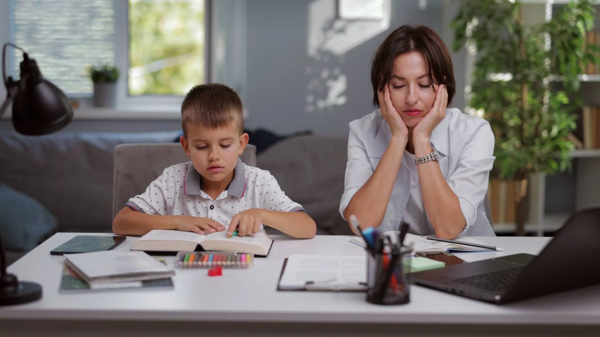 mama z synem wykonują swoje zadania: dziecko dorabia lekcje, mama pracuje mama z synem wykonują swoje zadania: dziecko dorabia lekcje, mama pracuje
