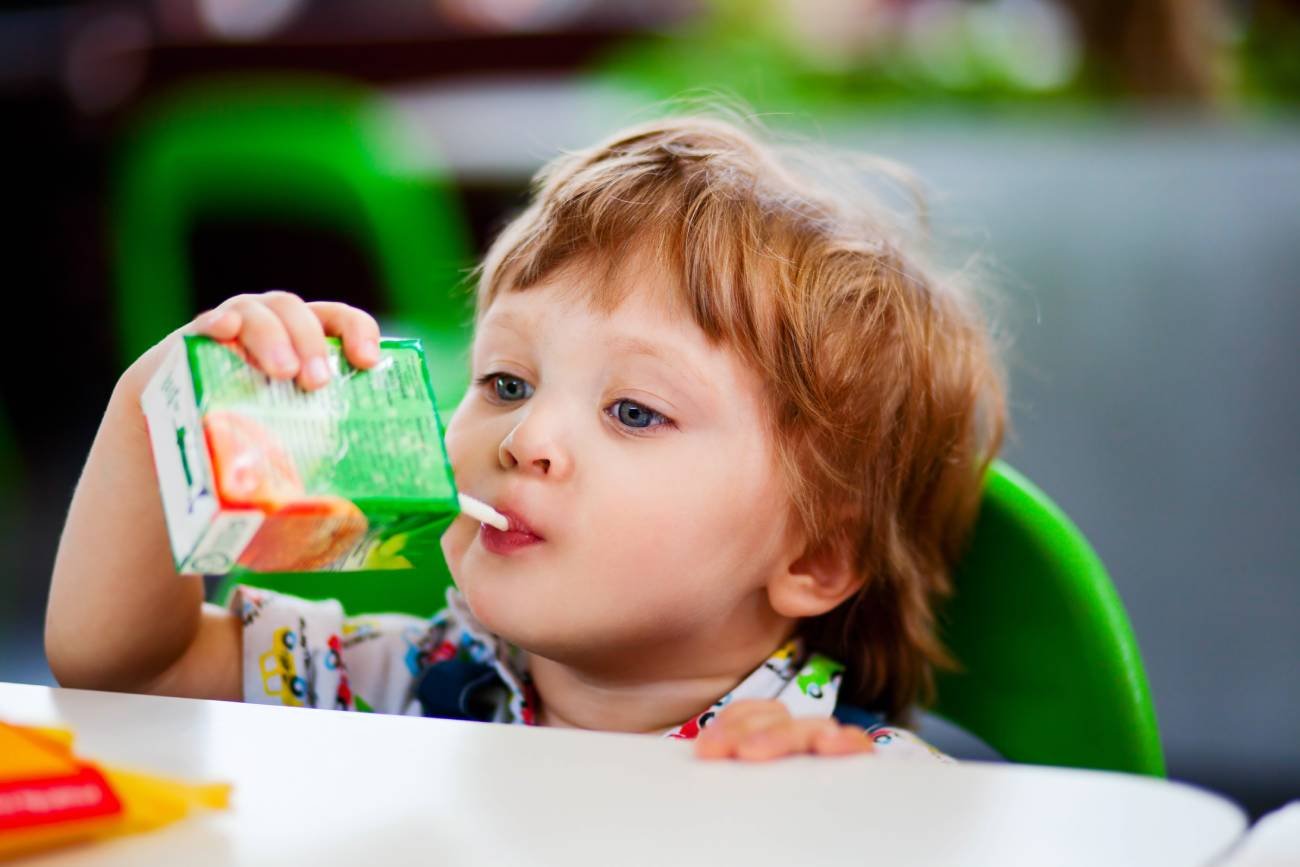 Małe dziecko pijące sok z kartonika ze słomką.