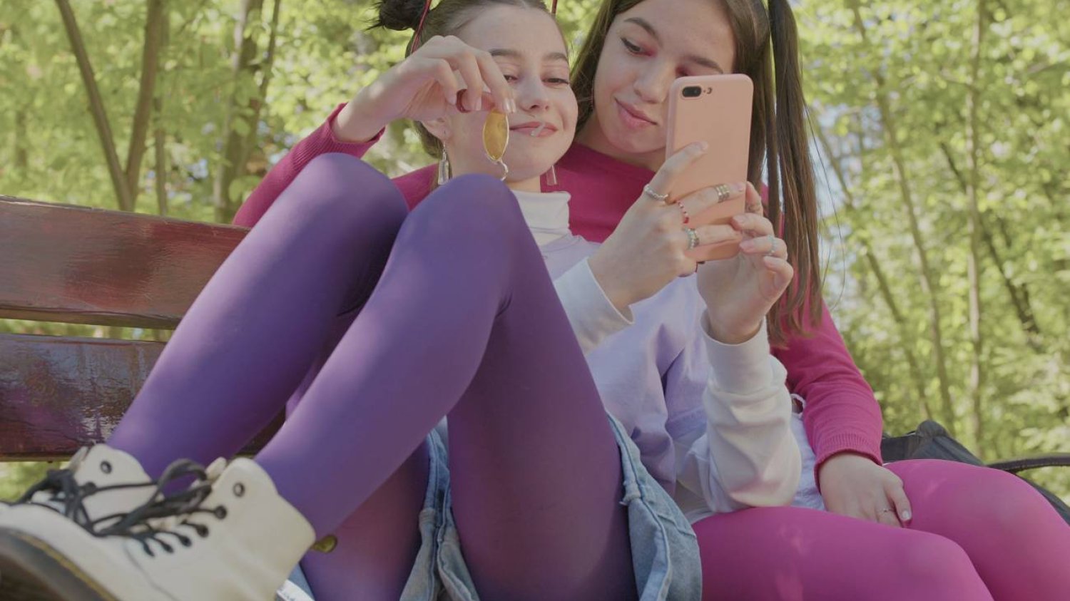 nastolatki w parku patrzą w ekran telefonu nastolatki w parku patrzą w ekran telefonu