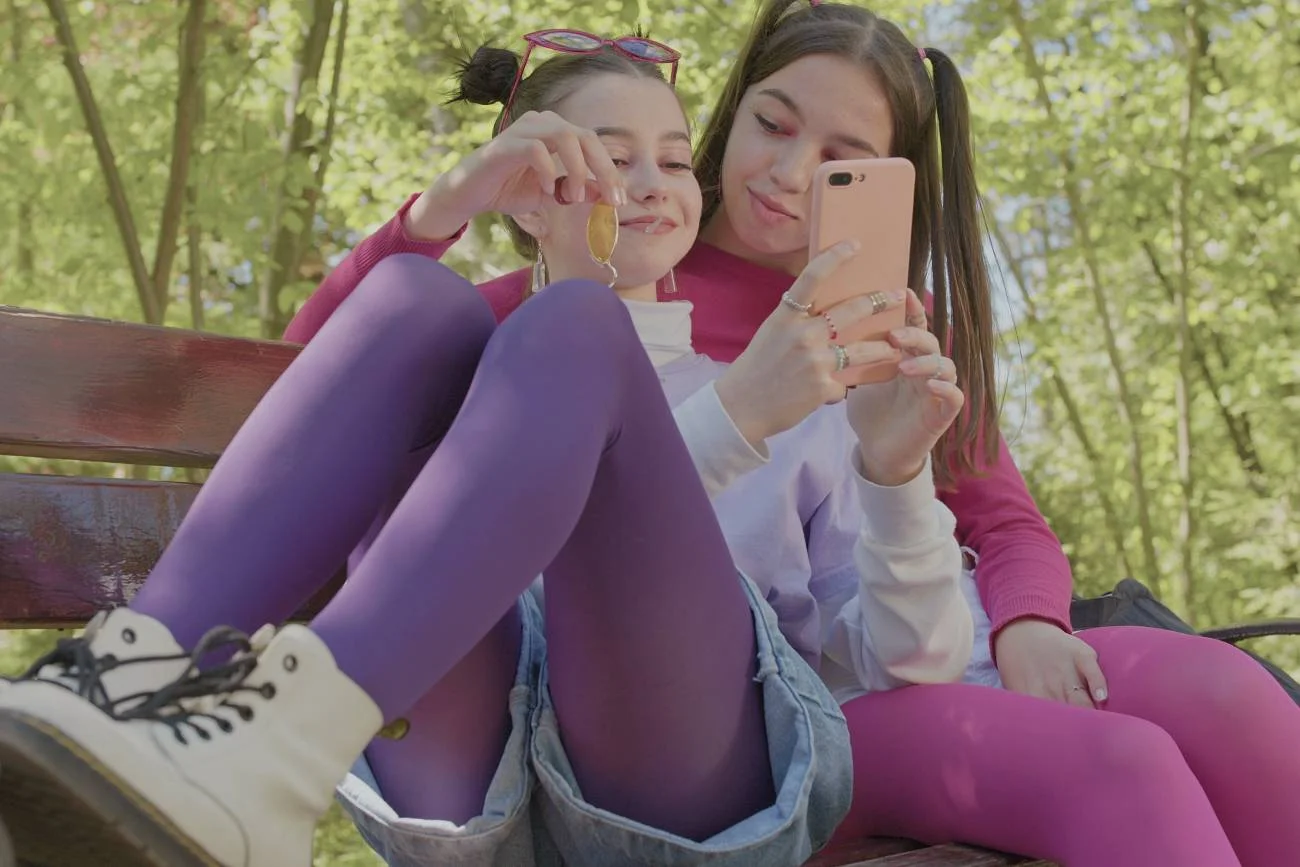 nastolatki w parku patrzą w ekran telefonu nastolatki w parku patrzą w ekran telefonu