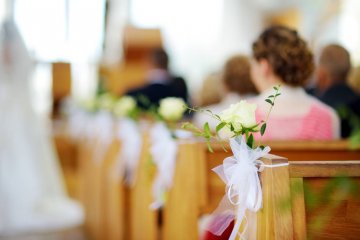 Ślub w kościele i goście siedzący w ławkach.