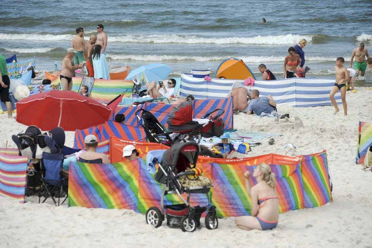 Mama pilnuje na plaży dziecka śpiącego w wózku.