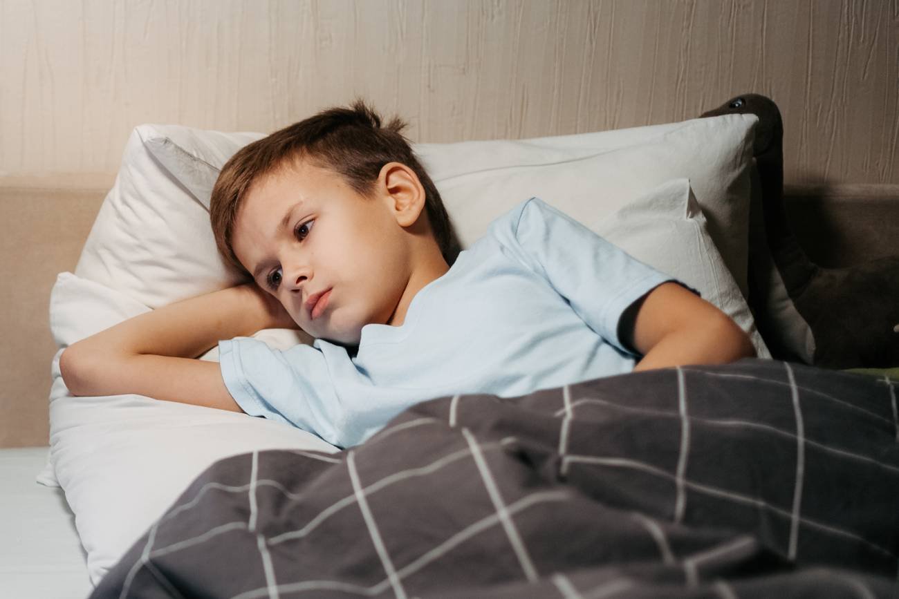 Chory chłopiec leży w łóżku.