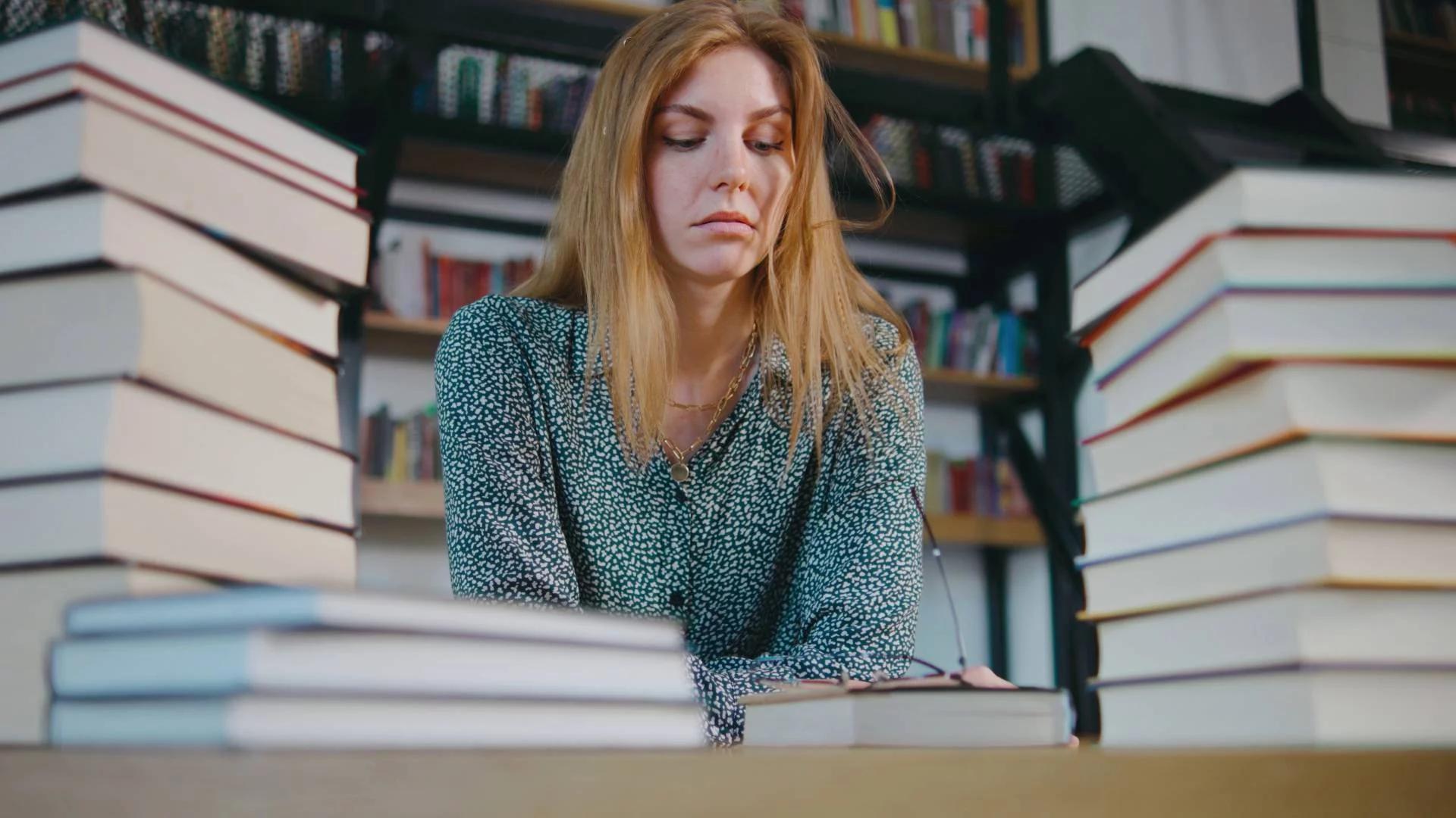 zmęczona nauczycielka siedzi przy biurku pełnym książek