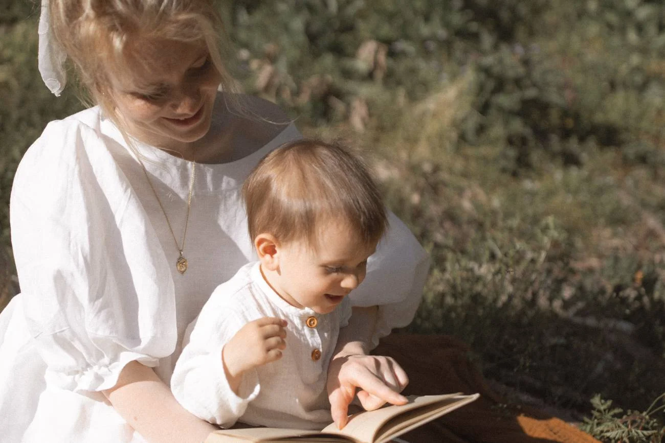 Mama i dziecko spędzają razem czas: czytają książkę na kocu.
