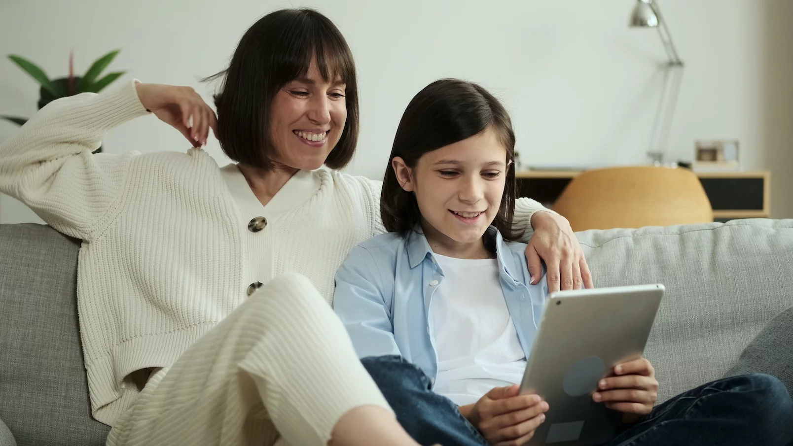Mama z dzieckiem siedzą na kanapie i patrzą w tablet