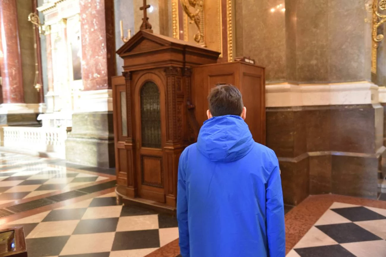 Mężczyzna stoi przed konfesjonałem w kościele. Mężczyzna stoi przed konfesjonałem w kościele.