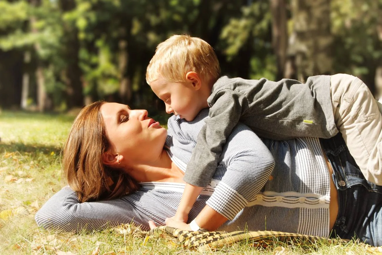 Mama i wysoko wrażliwe dziecko bawią się na trawie.