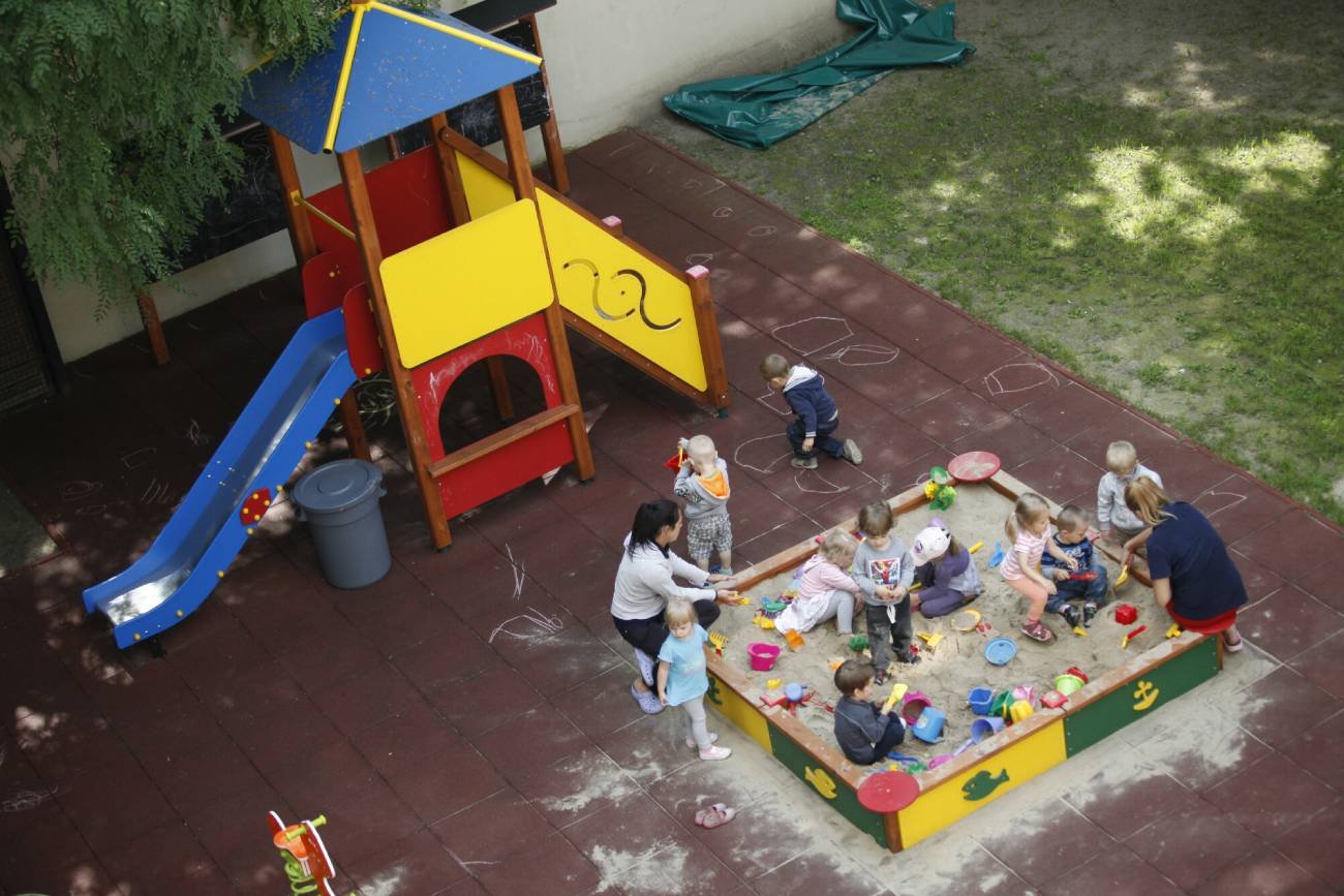 Dzieci bawiące się na placu zabaw przy żłobku.