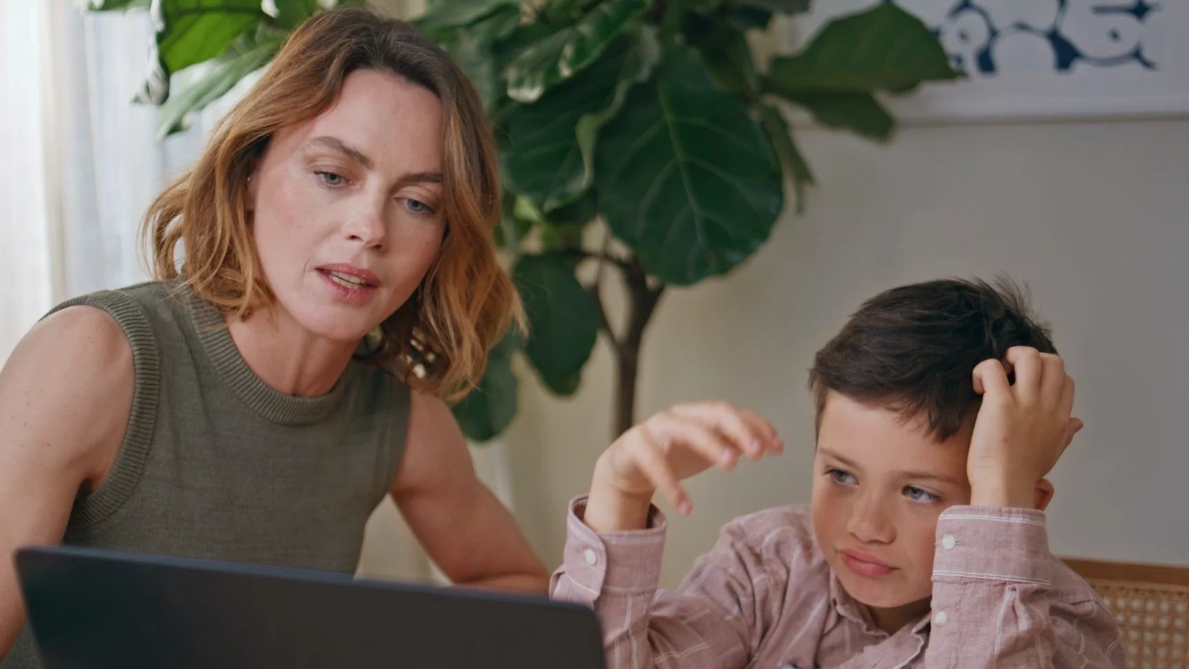 Na zdjęciu mama i dziecko odrabiają lekcje. Dziecko ma zniesmaczoną minę.
