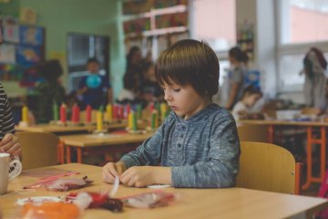 Przedszkolak robi pracę plastyczną przy stoliku.