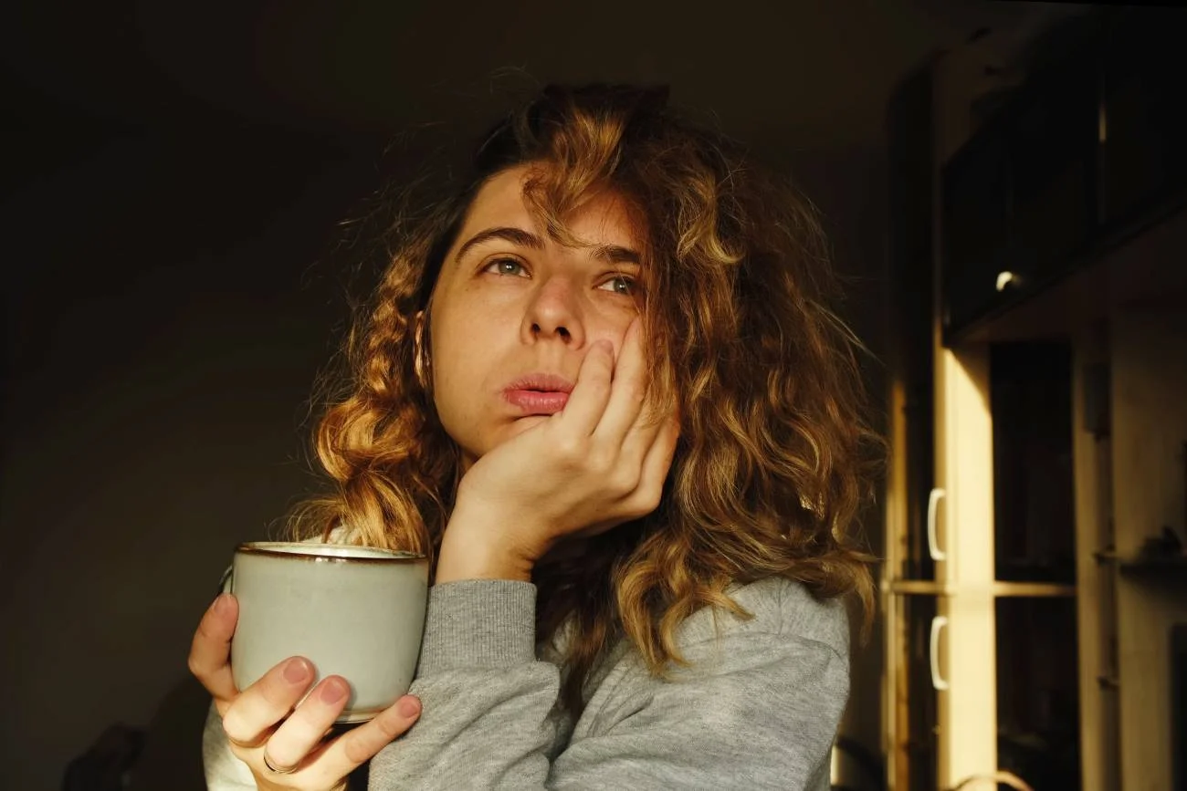 Zmęczona, smutna mama pije kawę i patrzy w dal