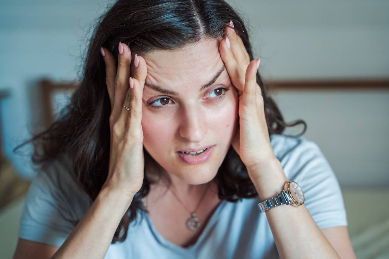 Zestresowana mama trzyma się za skronie.