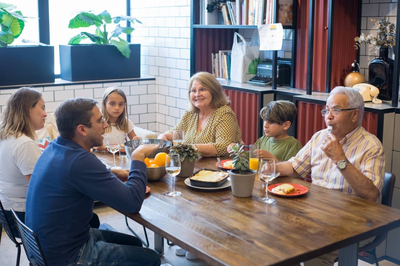Wielopokoleniowa rodzina siedzi przy stole i rozmawia.