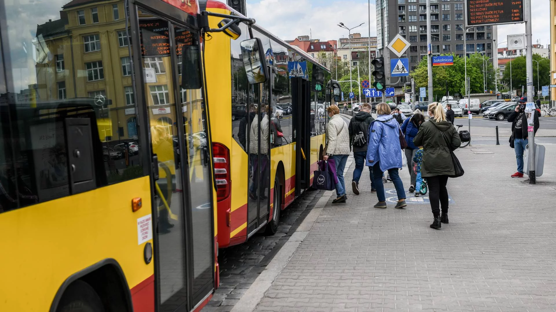 miejski autobus na przystanku, pasażerowie wsiadają do niego