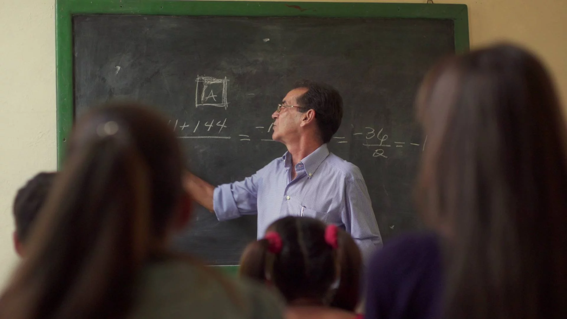 nauczyciel pisze na tablicy i tłumaczy materiał uczniom w klasie nauczyciel pisze na tablicy i tłumaczy materiał uczniom w klasie