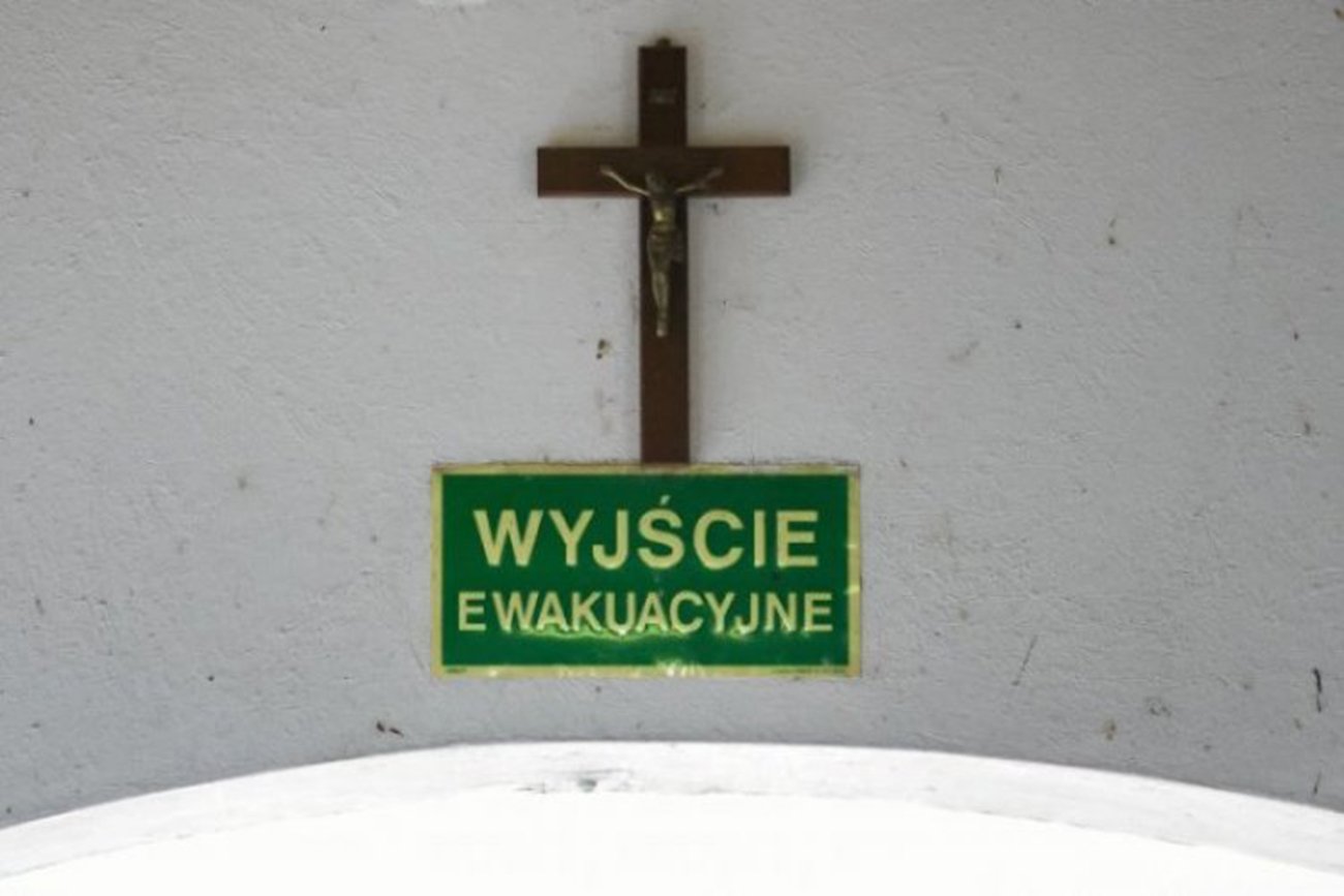 Krzyż na ścianie i napis: "wyjście ewakuacyjne"