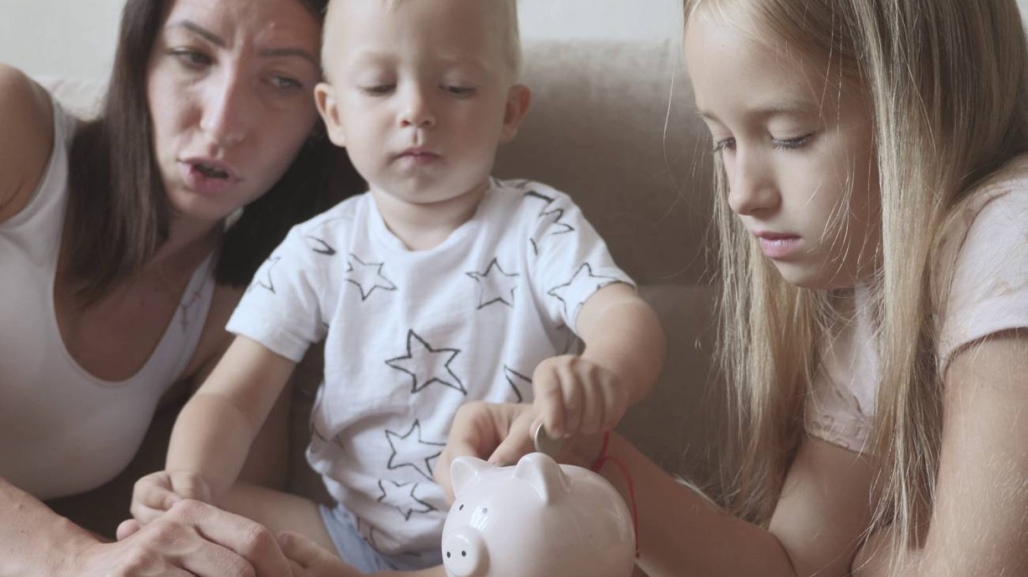 mama z dziećmi wrzuca pieniądze do skarbonki mama z dziećmi wrzuca pieniądze do skarbonki