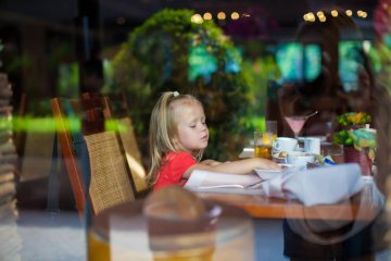 Mała dziewczynka siedzi przy stole w restauracji.