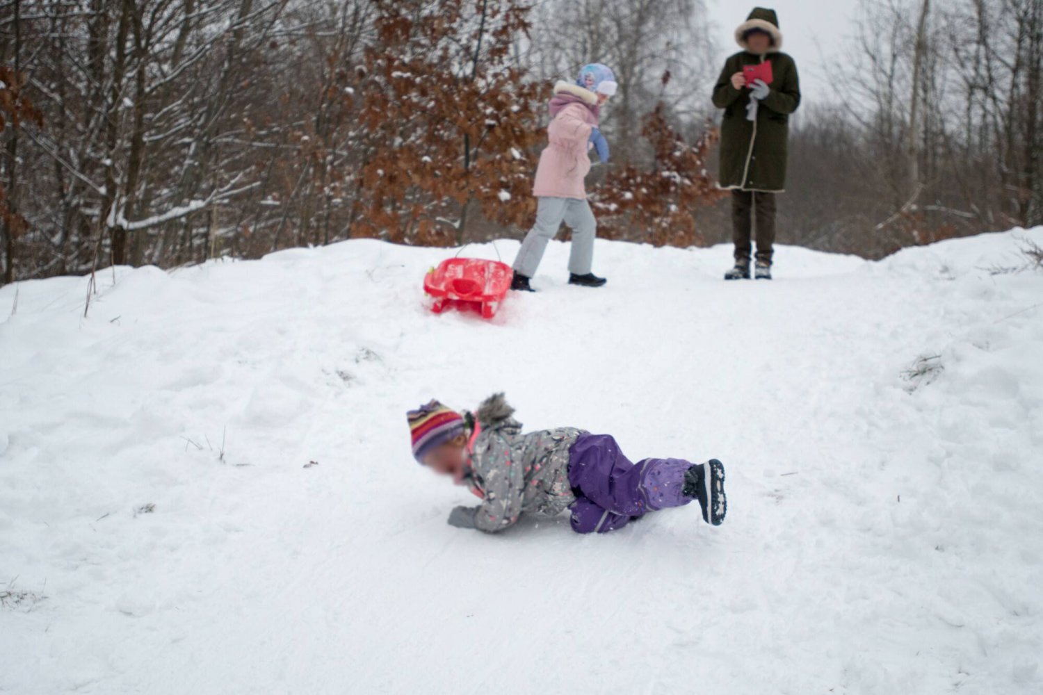 Babcia pilnuje wnuków podczas zabawy na śniegu.