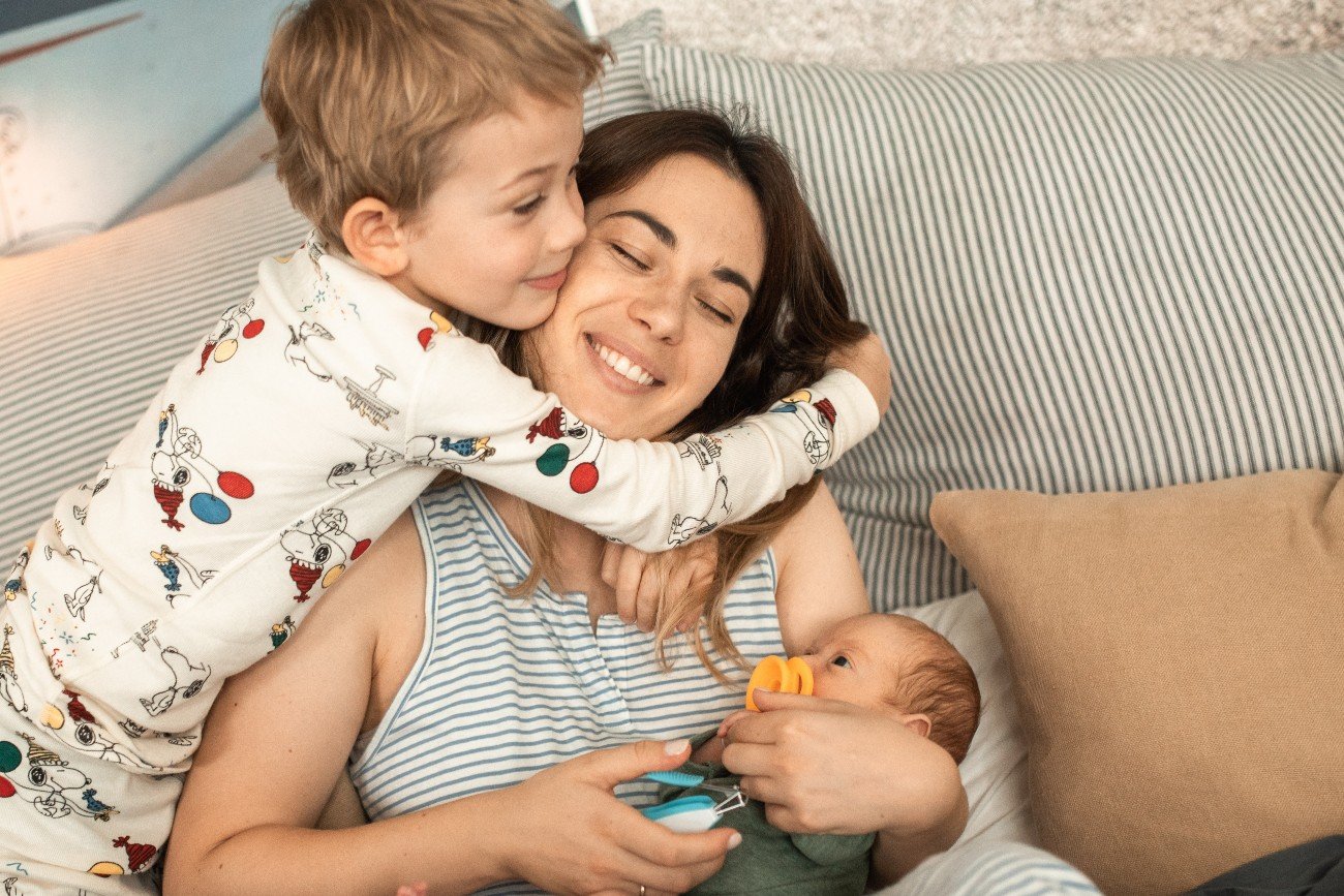 Mama przytula małe dziecko i niemowlę.