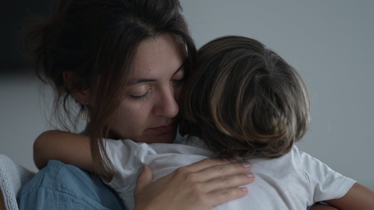 Wypalenie rodzicielskie Na zdjęciu zmęczona mama przytula dziecko.