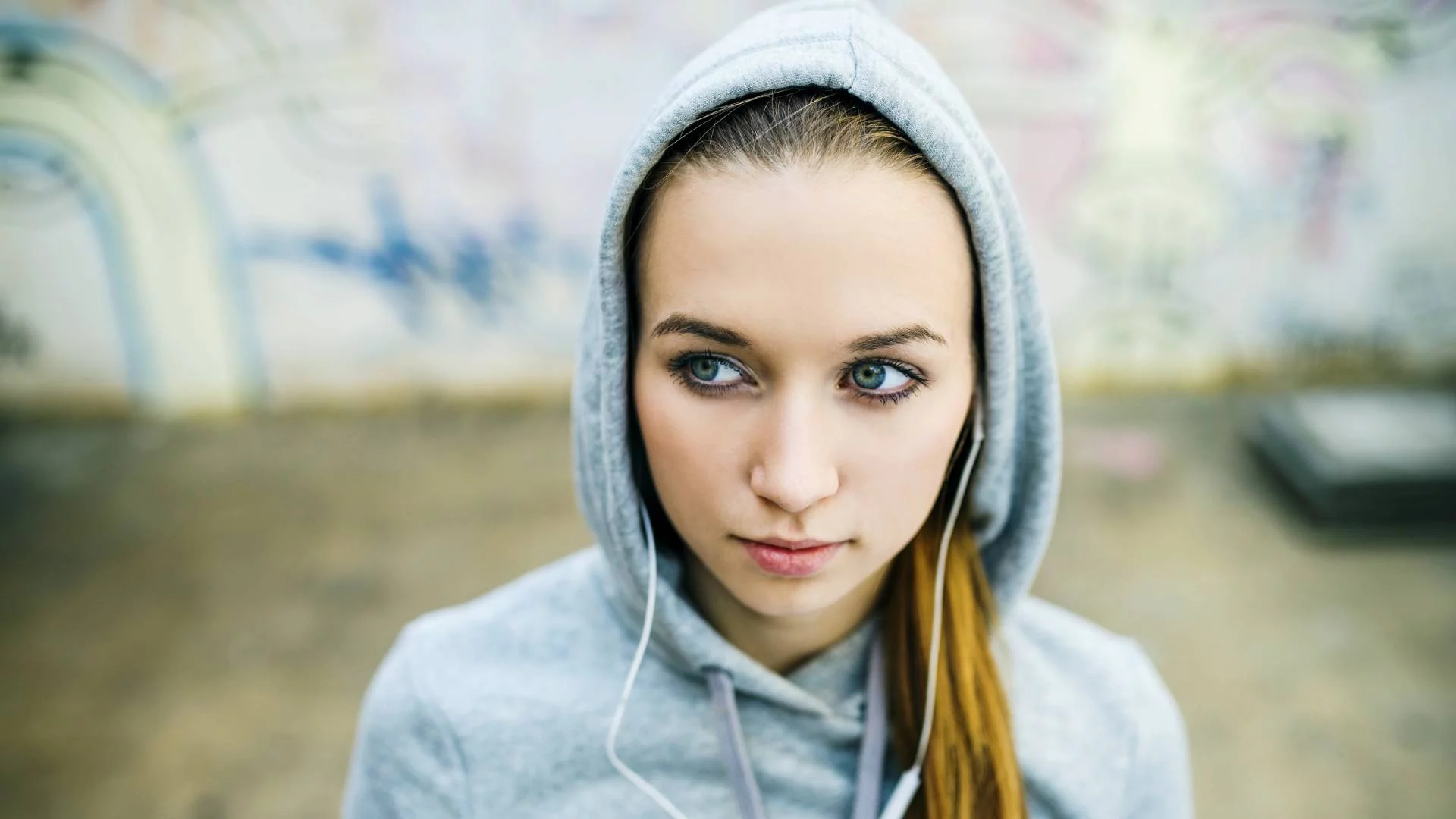 młoda kobieta w słuchawkach na uszach i kapturze bluzy na głowie młoda kobieta w słuchawkach na uszach i kapturze bluzy na głowie