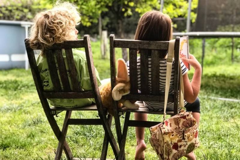 Chłopiec i dziewczynka w ogrodzie, rodzeństwo siedzi na krzesłach