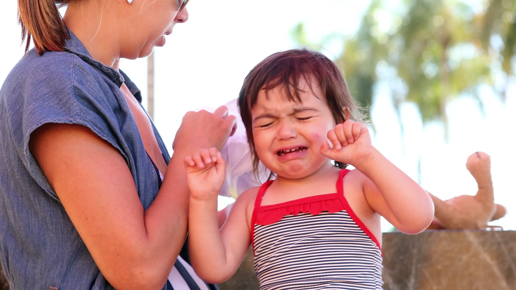 Na zdjęciu małą dziewczynka płacze. Obok jest jej mama.
