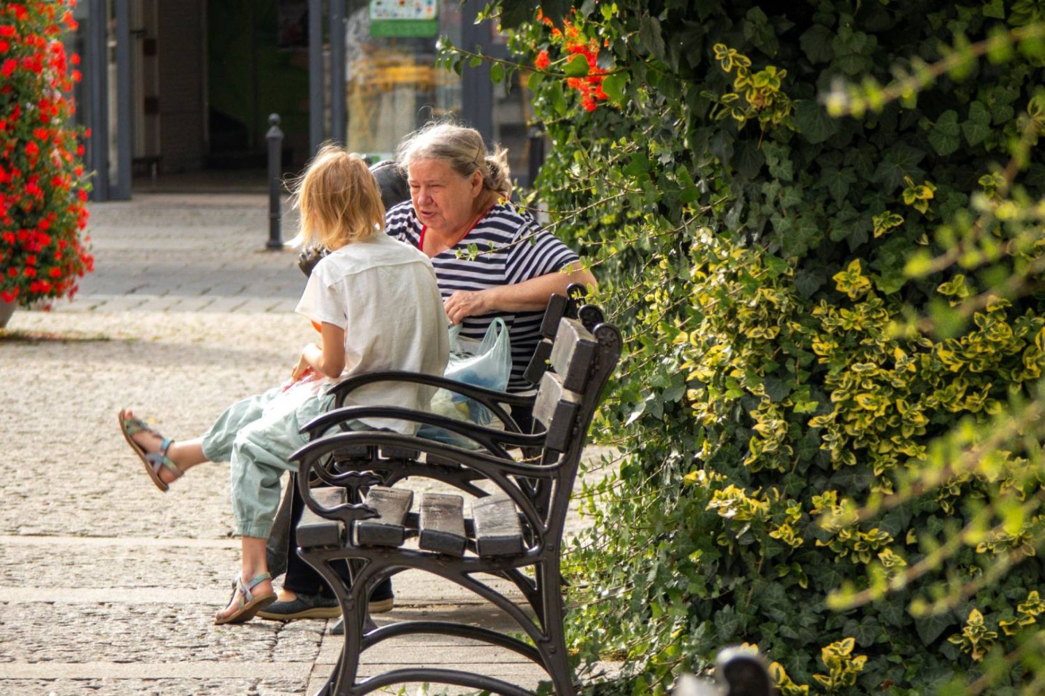 babcia z wnuczką rozmawia, siedząc na ławce