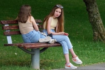 Nastolatki rozmawiają na ławce w parku.