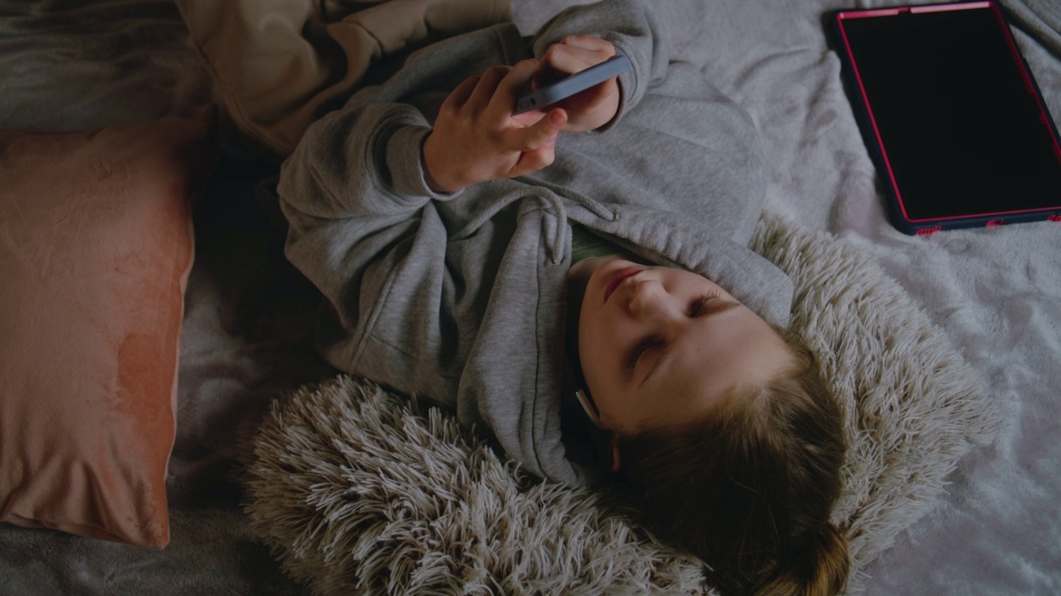 Nastolatki skippują rzeczywistość Na zdjęciu nastolatka leży na łóżku i patrzy w telefon.