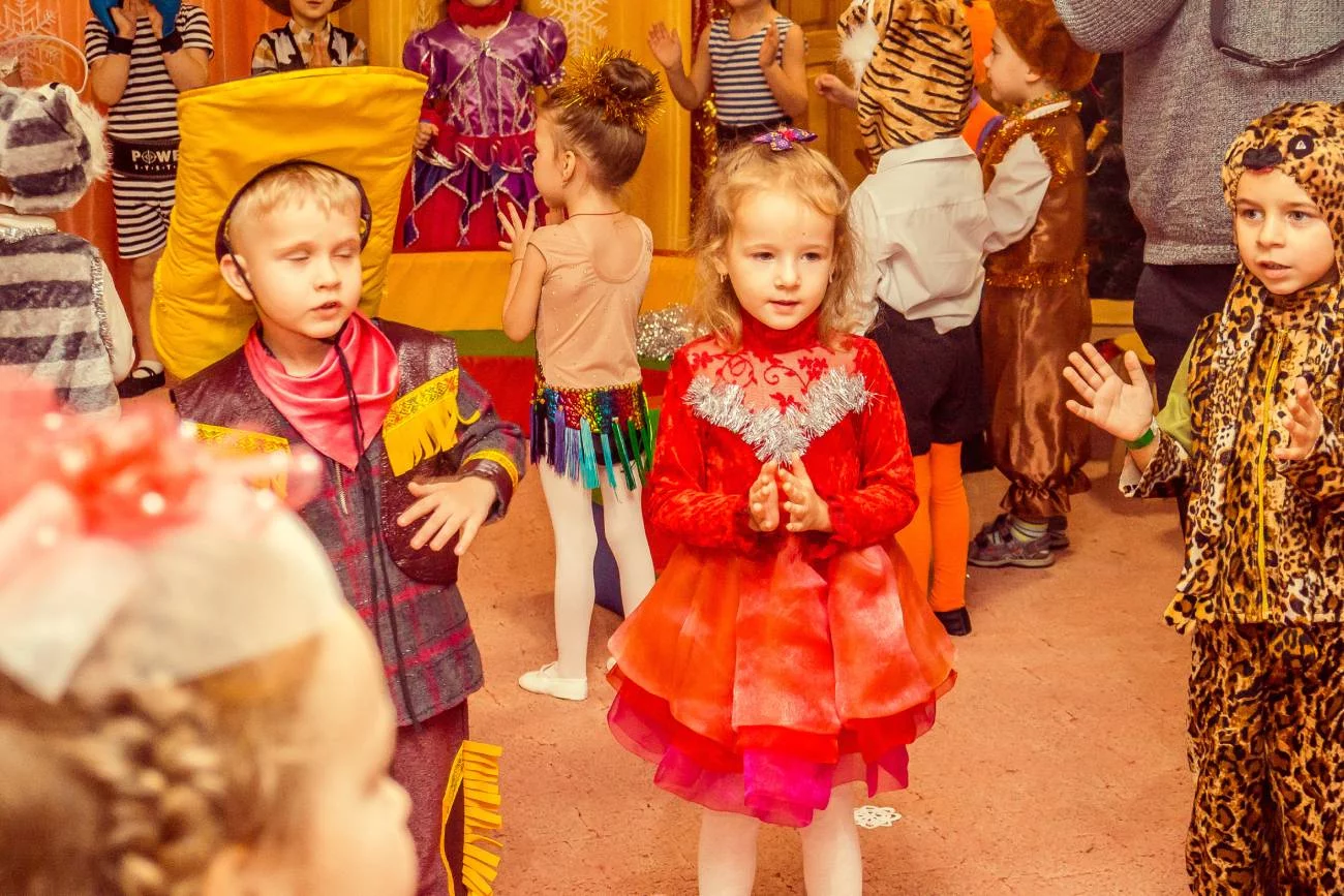 Dzieci w przebraniach bawią się na balu karnawałowym w przedszkolu.